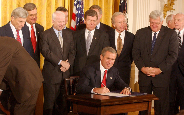 Surrounded by members of Congress during a ceremony in the East Room of the White House Oct. 16, 2002, President George W. Bush signs the congressional resolution authorizing U.S. use of force against Iraq. (Newscom/UPI Photo Service/Chris Corder)