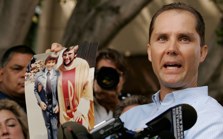 Plaintiff Lee Bashforth holds a photo of himself outside Los Angeles Superior Court on July 16, 2007, the day that the Los Angeles archdiocese and attorneys for more than 500 victims of clergy sex abuse arrived at a $660 million settlement. (AP Photo/Damian Dovarganes)