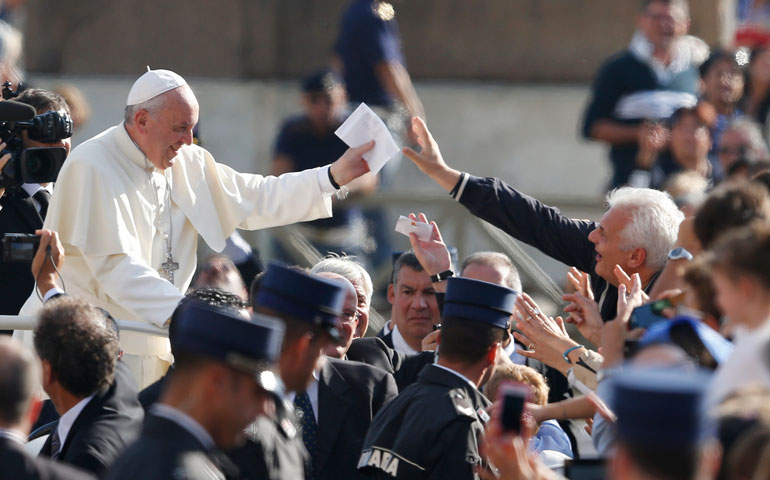 Pope Francis accepts a letter from a pilgrim as he arrives to lead his general audience in St. Peter's Square at the Vatican Oct. 16. (CNS/Paul Haring)