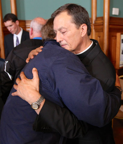 Fr. Charles Lachowitzer, moderator of the curia and vicar general in the St. Paul-Minneapolis archdiocese, hugs an abuse survivor after a news conference to announce a settlement in St. Paul, Minn., on Oct. 13, 2014. (CNS/The Catholic Spirit/Dave Hrbacek)