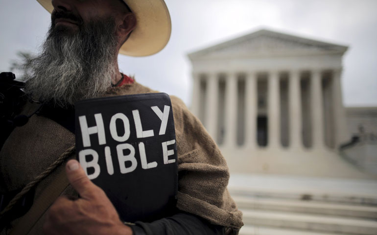 A protester holds a copy of the Bible outside of the U.S. Supreme Court building in Washington June 15. The court June 18, 2015, ruled that a town in Arizona violated a local church’s free speech rights by preventing it from posting signs notifying the public of its worship services. (CNS/Reuters/Carlos Barria)