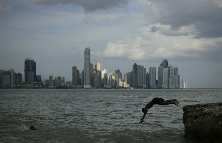 The skyline of Panama City is seen in the distance as boy jumps into the sea in a January 2011 file photo. (CNS/Juan Carlos Ulate, Reuters)
