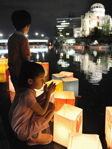 A girl prays after releasing a paper lantern Aug. 6, 2012, on the Motoyasu River facing the gutted Atomic Bomb Dome on the 67th anniversary of the bombing of Hiroshima, Japan. More than 75,000 people were killed in Hiroshima when the United States dropped the bomb near the end of World War II. (CNS photo/Kyodo, Reuters)