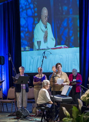 Projected on a screen above choir Archbishop Carlo Maria Vigano, apostolic nuncio to the United States, celebrates Mass Aug. 14 during the Leadership Conference of Women Religious assembly. (CNS photo/Roberto Gonzalez)