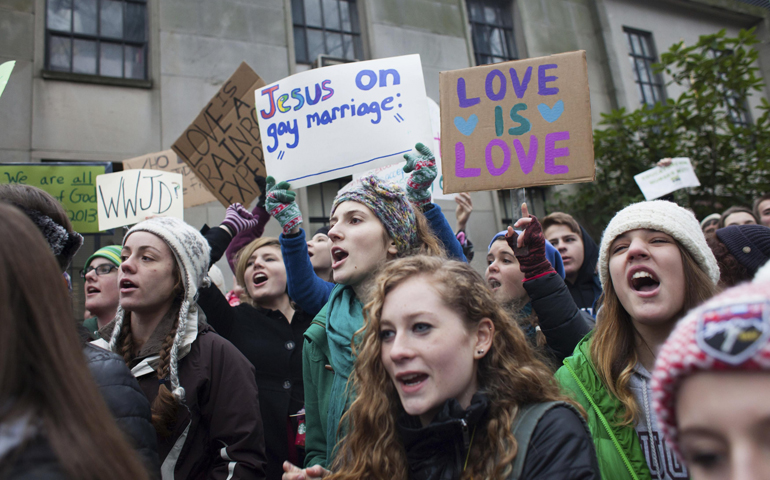 Eastside Catholic School students display signs during a rally in support of the school's former vice principal, Mark Zmuda, outside the Seattle archdiocese's chancery building Dec. 20. (CNS/Reuters/David Ryder)