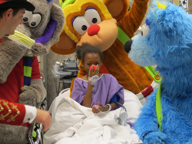Ringmaster Rizzo, Splash, Myles and Buddy the Bear of the Fur Circus visit a sick child in Nemours Children's Hospital Dec. 9 in Orlando, Fla. The troupe works almost year-round at professional baseball and hockey events across North America. (CNS photo/ courtesy Fur Circus)