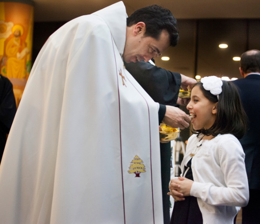 Perla Akiki receives Communion from her father, Fr. Wissam Akiki, after he was ordained to the priesthood Feb. 27 at St. Raymond's Maronite Cathedral in St. Louis. Akiki, who is married with a daughter, is the first married man to be ordained a priest for the U.S. Maronite Catholic Church. (CNS/St. Louis Review/Lisa Johnston)