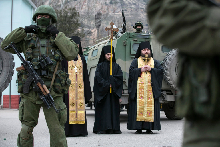 Orthodox clergymen pray next to armed servicemen near Russian army vehicles outside a Ukrainian border guard post in Ukraine's Crimean region March 1. (CNS/Reuters/Baz Ratner, Reuters) 