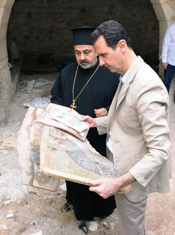 Syrian President Bashar Assad looks at destroyed religious artwork with a member of the clergy during a visit to the ancient Christian town of Maaloula, Syria, April 20, 2014. (CNS/Syria's national news agency handout via Reuters)