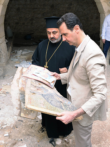 Syrian President Bashar al-Assad looks at destroyed religious artwork in 2014, in Maaloula, Syria. (CNS/Syria's national news agency handout via Reuters)