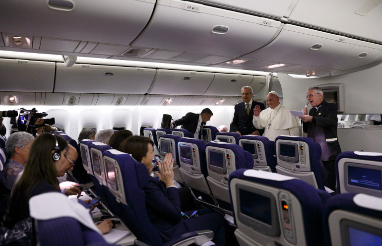 Pope Francis greets journalists aboard the flight from Tel Aviv to Rome May 26. At right is Jesuit Father Federico Lombardi, Vatican press spokesman. (CNS/Paul Haring)