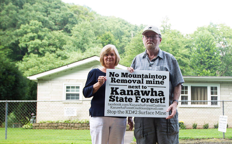 Stephen and Virginia Comer of Loudendale, W. Va., hold a sign voicing their protest against mountaintop removal coal mining, Aug. 18. The couple lives near Kanawha State Forest, and are concerned their home will be endangered by flooding from mining on the forest's edge. (CNS photo/Tyler Orsburn)