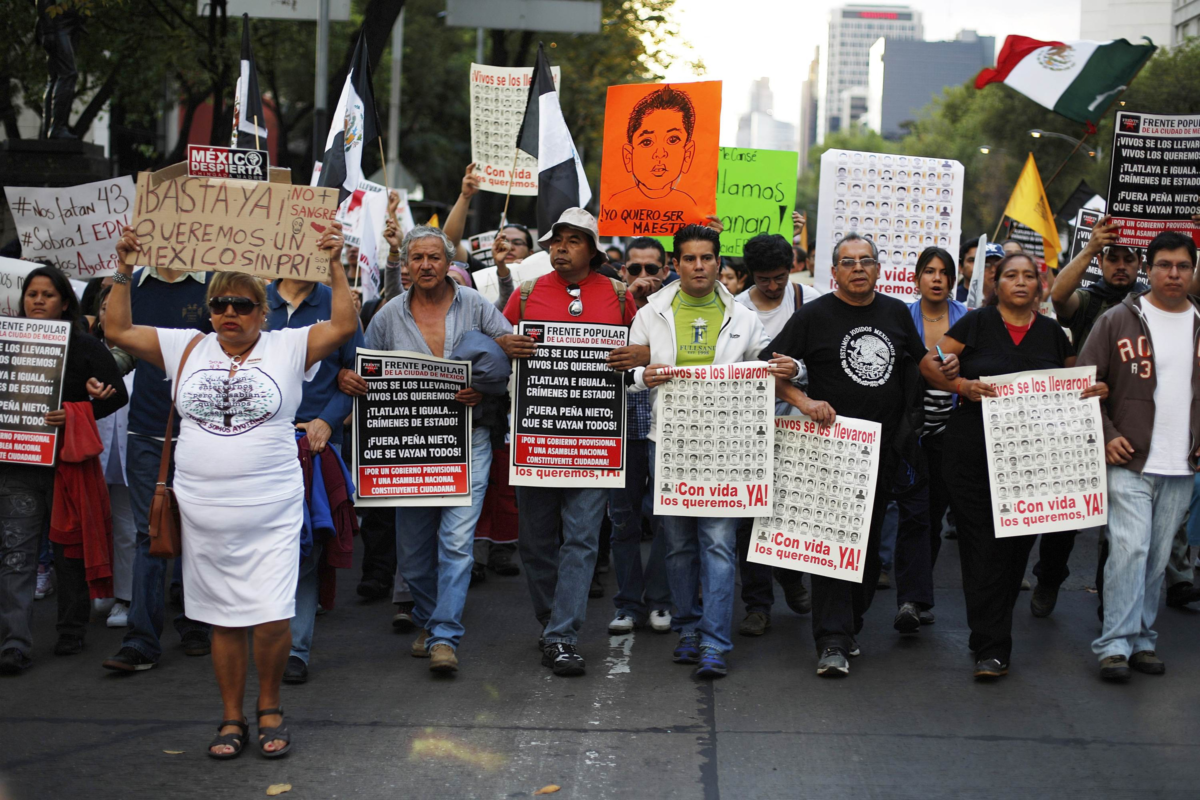 People hold posters and placards during a Nov. 16 march for the 43 missing trainee teachers in Mexico City. The remains of a Ugandan missionary priest missing for months were recovered from a mass grave in Mexico, adding to the horror of the crimes and killings in the region. (CNS/Reuters) 