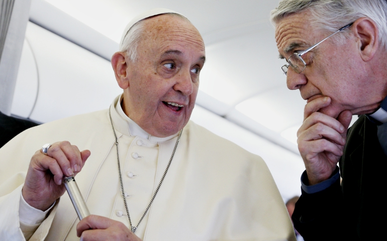 Pope Francis consults with Jesuit Fr. Federico Lombardi while answering a reporter's question on his flight back to Rome from Strasbourg, France, in November 2014. (CNS/Paul Haring)