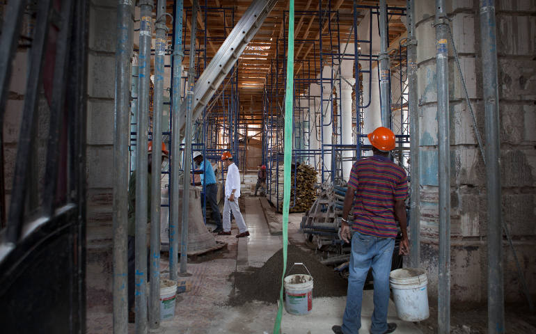 A worker carries a bucket in early September inside a church in Port-au-Prince, Haiti. Church and school reconstruction in Haiti has moved ahead with nearly $20 million allocated through the church-led PROCHE effort. (CNS photo/courtesy PROCHE, Haiti)