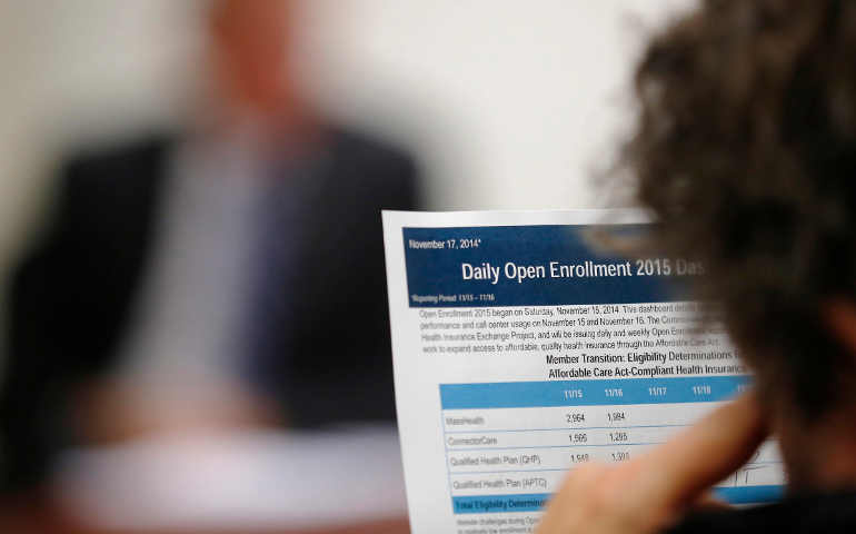 A reporter reads performance and usage data for open enrollment on Massachusetts’ health insurance website under the federal Affordable Care Act. (CNS file photo, 2014)