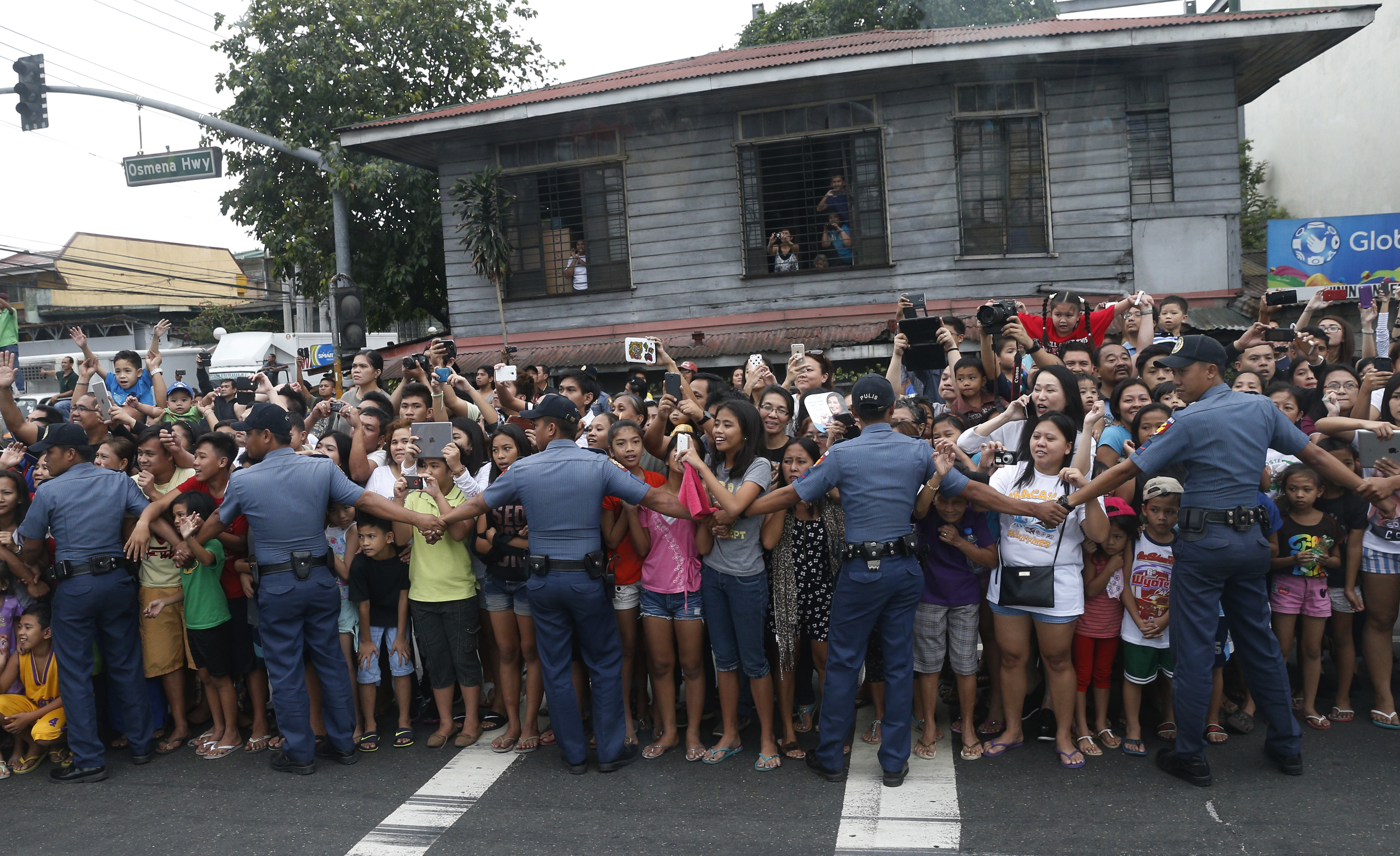 Police hold back the crowd lining the motorcade route as Pope Francis arrives back in Manila after celebrating a Mass adjacent to the airport in Tacloban, Philippines, Jan. 17. (CNS/Paul Haring) 