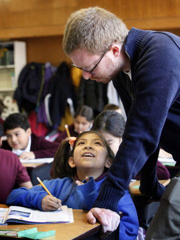 Fourth-grad teacher Ryan Gallagher asists student Britany Martinez with a geography question during class at St. Ann School in Chicago on Oct. 17, 2014. (CNS/Karen Callaway)