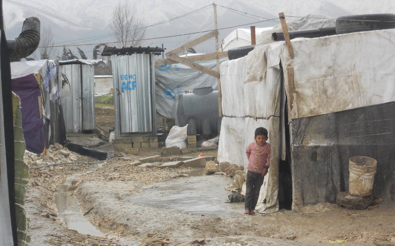 A Syrian child stands barefoot outside a tent Feb. 17 at a camp in Lebanon's Bekaa Valley. This winter's heavy rains have caused the paths between the tents at the settlements to fill with water. (CNS photo/Brooke Anderson)
