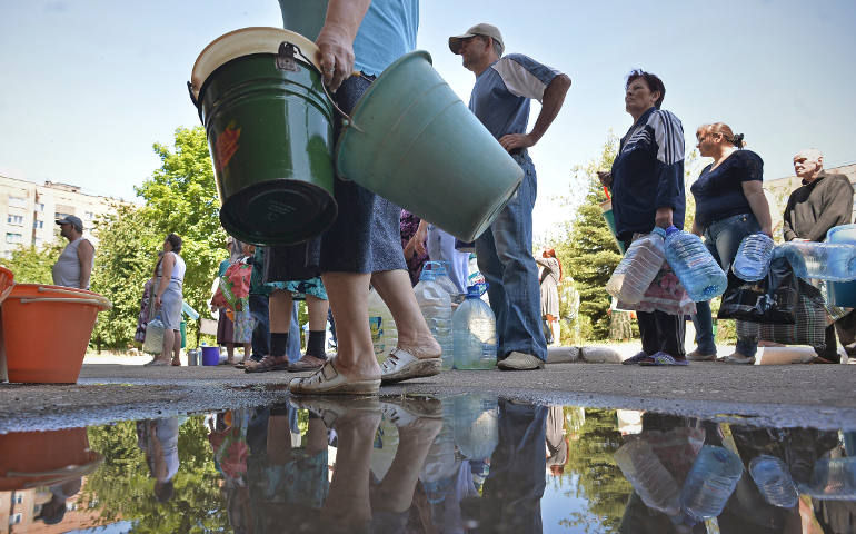 Residents near Kramatorsk, Ukraine, carry empty buckets and bottles to have them filled with potable water June 19, 2014, after a shelling from fighting with pro-Russian separatists reportedly destroyed a water supply system. (CNS photo/Valentina Svistun ova, EPA)