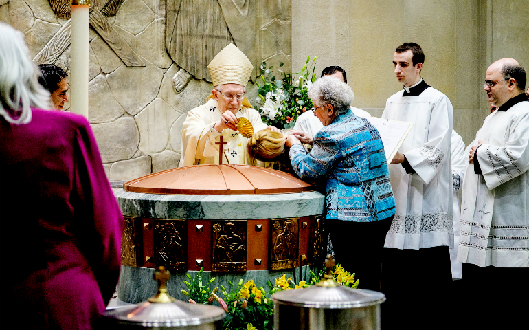 Archbishop Leonard Blair of Hartford, Conn., baptizes a young woman during the 2015 Easter Vigil at the Cathedral of St. Joseph in Hartford. The archdiocese recently announced plans to close and/or consolidate up to 100 parishes. (CNS/Bob Mullen)