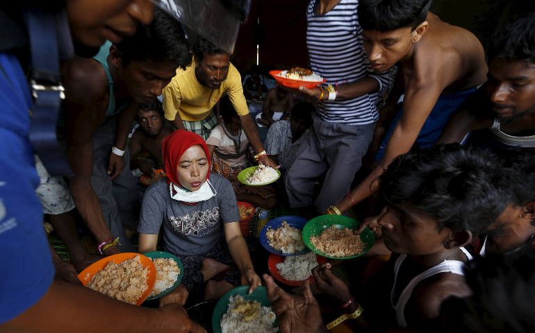 Bangladeshi migrants raise up their plates to ask for more food as breakfast is served by volunteers at a shelter in Kuala Langsa, in Indonesia's Aceh Province, May 19. Pope Francis said people must stop wasting, start sharing food and other resources. ( CNS photo/Beawiharta)