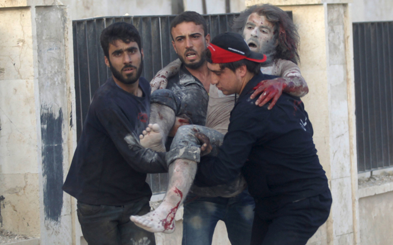 Men carry an injured man at a site damaged by what activists said was a shelling by forces of Syrian President Bashar Assad near Idlib, Syria, June 8, 2015 (CNS/Khalil Ashawi, Reuters)
