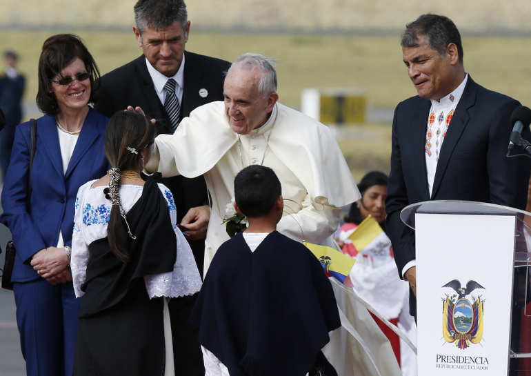 Pope Francis stands next to Ecuadorean President Rafael Correa, right, as he greets a girl upon his arrival at Mariscal Sucre International Airport in Quito, Ecuador, July 5. At left is the president's wife, Anne Malherbe Gosselin. (CNS photo/Paul Haring)
