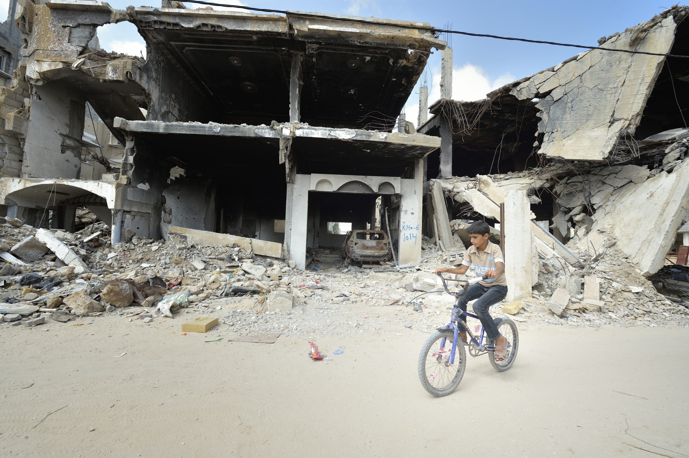A boy rides his bike amid the ruins of Khan Younis, Gaza Strip, June 9. (CNS/Paul Jeffrey) 