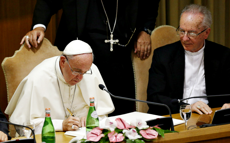 Pope Francis signs a declaration on climate change and human trafficking as Brazilian Cardinal Claudio Hummes, former prefect of the Congregation for the Clergy, looks on at the Vatican in July 2015. (CNS/Paul Haring)