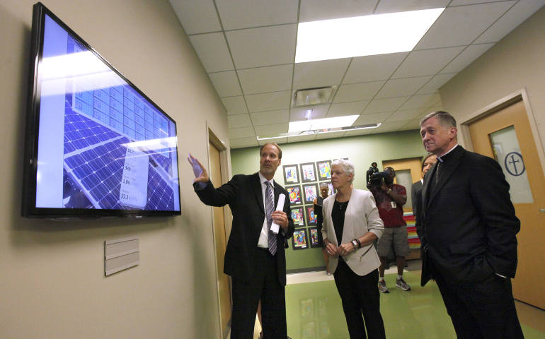 Archbishop Blase J. Cupich of Chicago, right, and Gina McCarthy, administrator of the U.S. Environmental Protection Agency, look over a board with Ted Hudon that displays the solar panel activity at Old St. Mary's School in Chicago July 24. (CNS photo/Karen Callaway, Catholic New World)
