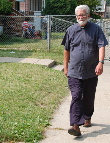 Fr. Bob Stiefvater, newly appointed pastor of All Saints Parish in Milwaukee, strolls through a neighborhood around the church on the city's north side July 10. He takes a daily walk in an effort to get to know the neighborhood and to let neighbors know of the church's presence. (CNS photo/Ricardo Torres, Catholic Herald)