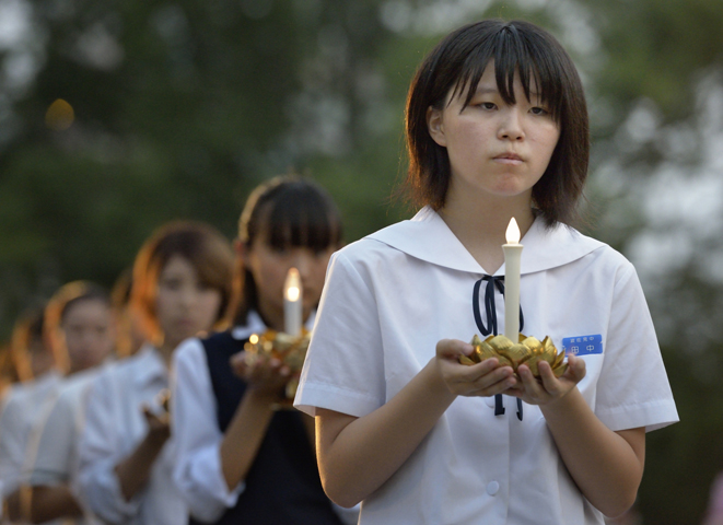A young woman carries a candle in a procession at the beginning of an Aug. 8 interfaith service in Nagasaki, Japan, to commemorate those who died as the result of the U.S. atomic bomb dropped on the city in 1945. Participants in the service included Bishop Oscar Cantu of Las Cruces, N.M. (CNS photo/Paul Jeffrey)