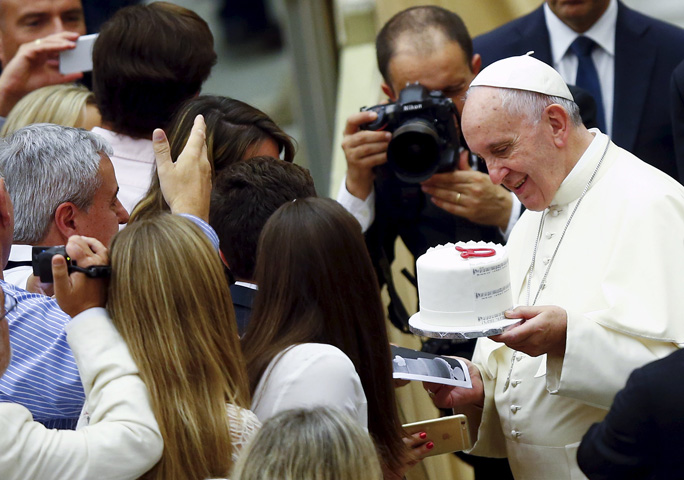 Pope Francis holds a cake he received from a newly married couple during his weekly audience in Paul VI hall at the Vatican Aug. 12. (CNS photo/Remo Casilli, Reuters)