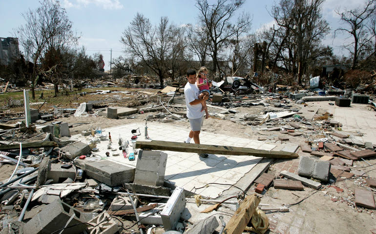 A father and daughter walk through rubble in September 2005 in Biloxi, Miss., after Hurricane Katrina devastated the Gulf Coast community. The hurricane and the failure of the New Orleans levees Aug. 29, 2005, caused more than 1,800 deaths across the coast and damaged or destroyed more than a million houses and businesses. (CNS photo/Bob Roller)