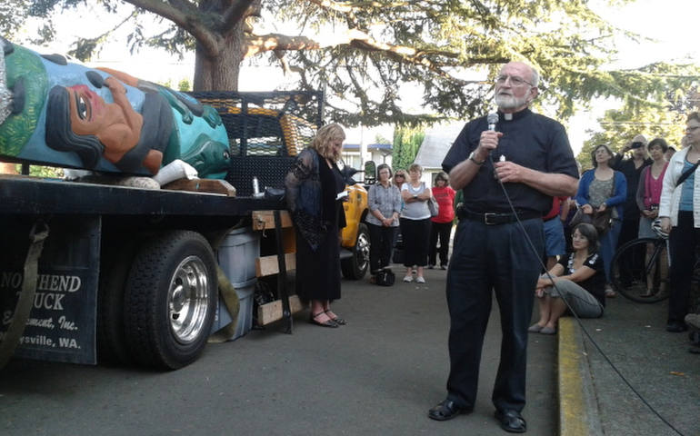 Paulist Fr. Charlie Brunick, pastor of St. Philip Neri Parish in Portland, Ore., offers a blessing Aug. 24 on a totem pole carved as a sign of opposition to planned coal exports that would bring trains through the Pacific Northwest. (CNS photo/Ed Langlois, Catholic Sentinel)