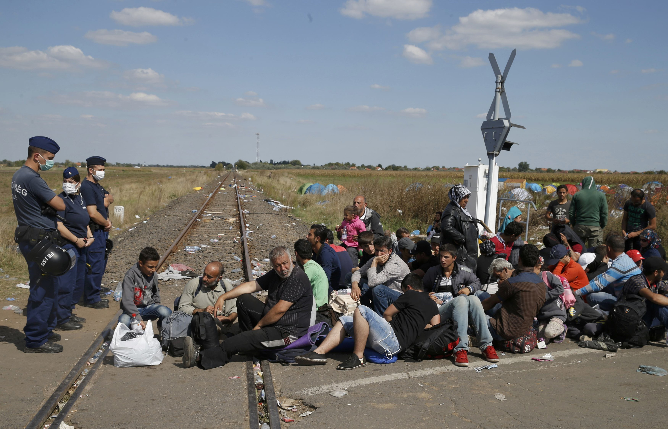 Hungarian policemen watch migrants near a collection point in Roszke Sept. 9. (CNS/Marko Djurica, Reuters)