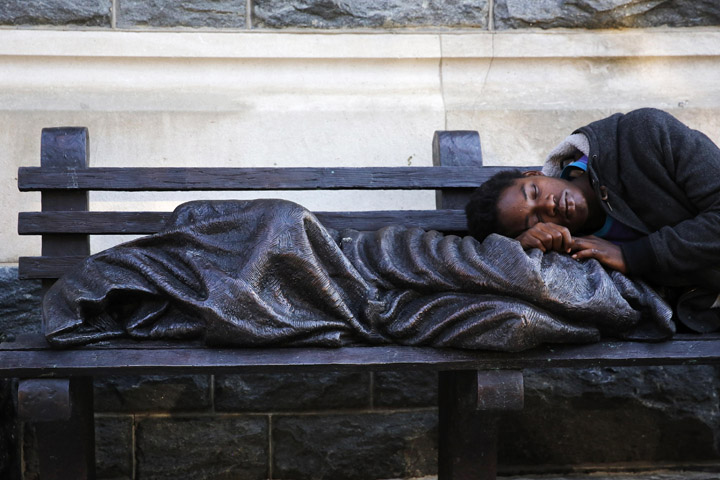 A man sleeps on a sculpture titled "Homeless Jesus" in front of the offices of Catholic Charities of the Archdiocese of Washington Sept. 16. (CNS/Jonathan Ernst, Reuters)
