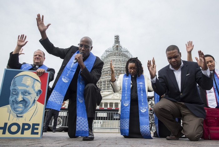 Faith leaders pray as low-wage contract workers from the U.S. Capitol and other federal buildings rally during a strike over wages in Washington Sept. 22. The group invoked the name of Pope Francis as they demonstrated for higher pay ahead of the pontiff's arrival in the nation's capital. (CNS photo/Joshua Roberts) 