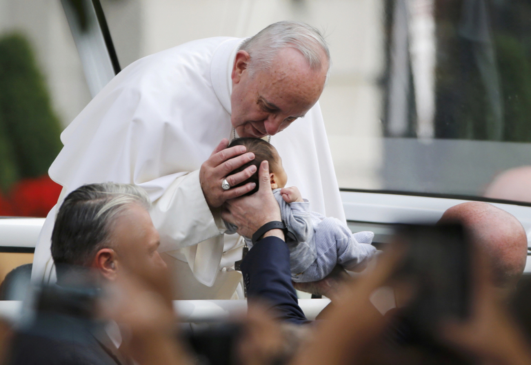 Pope Francis stops to kiss a child as he makes his way in the popemobile to Independence Hall in Philadelphia Sept. 26. (CNS/Jim Bourg, Reuters)