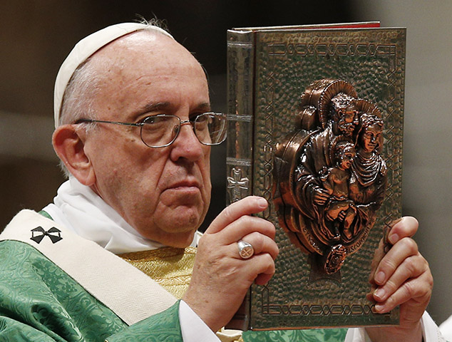 Pope Francis raises the Book of the Gospels during the opening Mass of the Synod of Bishops on the family in St. Peter's Basilica at the Vatican Oct. 4. The cover of the book is decorated with an image of the Holy Family. (CNS/Paul Haring)