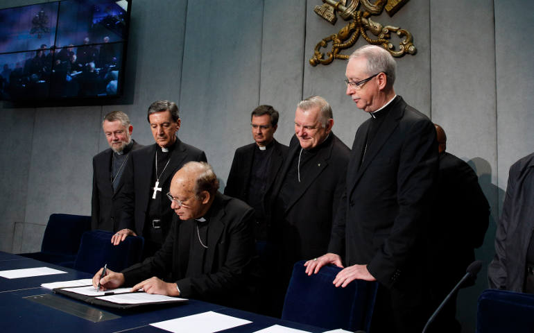 Cardinal Oswald Gracias of Bombay, India, signs a document at an Oct. 26 Vatican news conference in which leaders of the world's regional bishops conferences appealed for action on climate change. (CNS photo/Paul Haring)