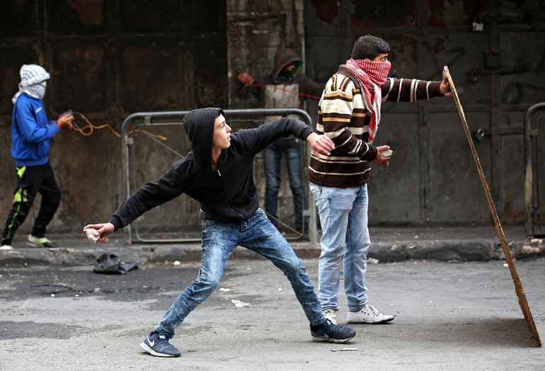 Palestinian protesters throw stones at Israeli soldiers during clashes in Hebron, West Bank, Nov. 5.(CNS/Abed Al Hashlamoun, EPA) 