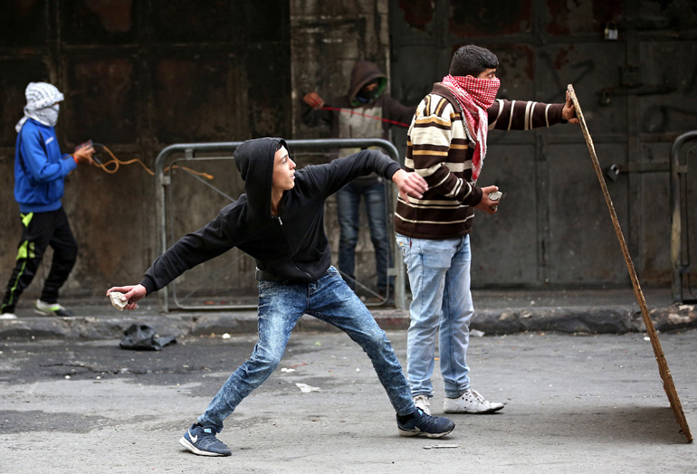 Palestinian protesters throw stones at Israeli soldiers during clashes in Hebron, West Bank, Nov. 5.(CNS/Abed Al Hashlamoun, EPA)