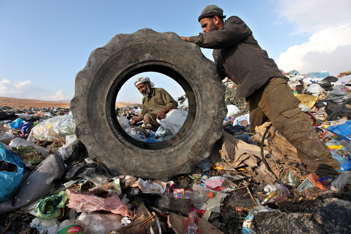 In this Oct. 26, 2011, file photo, Palestinians sift through garbage that was dumped in the West Bank. Some doctors say patients have a right to have causes of illness, especially from environmental pollution, studied as part of their care. (CNS/Abed Al Hashlamoun, EPA) 