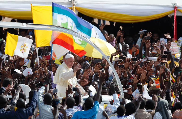 The Vatican flag and a peace banner are seen as Pope Francis greets the crowd as he arrives for a meeting with young people at the Kololo airstrip in Kampala, Uganda Nov. 28. (CNS photo/Paul Haring)