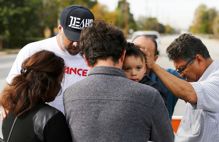 Neighbors pray with a family prevented from returning to their home Dec. 3 in San Bernardino, Calif. (CNS/Mike Blake, Reuters)
