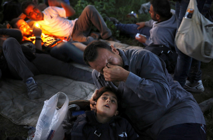 A Syrian refugee cries next to his 7-year-old daughter after crossing the border into Macedonia in early May near the Greek village of Idomeni. (CNS/Yannis Behrakis, Reuters)