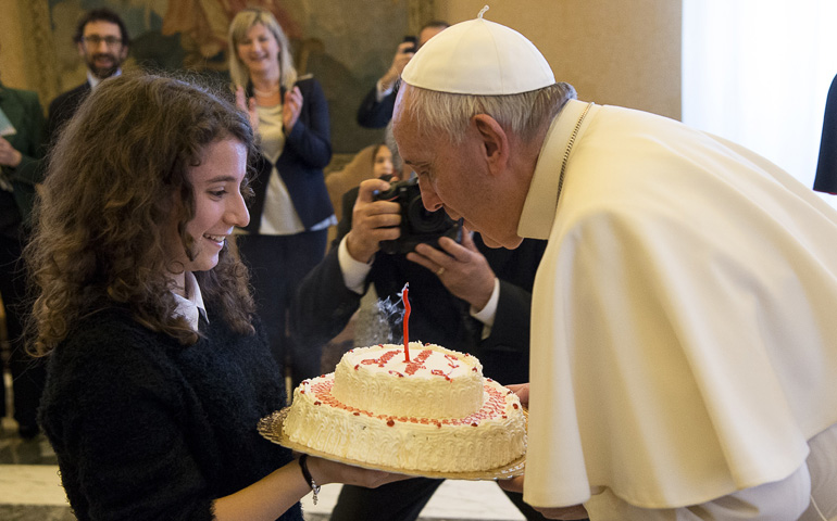 Pope Francis blows out the candle on a birthday cake presented by a young member of the Italian branch of Catholic Action during an audience with the group at the Vatican Dec. 17. (CNS/L'Osservatore Romano, handout)
