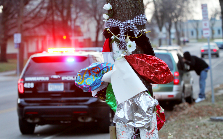 Balloons, flowers and signs seen in December 2015 mark the site where Minneapolis police shot Jamar Clark. (CNS/The Catholic Spirit/Dave Hrbacek)
